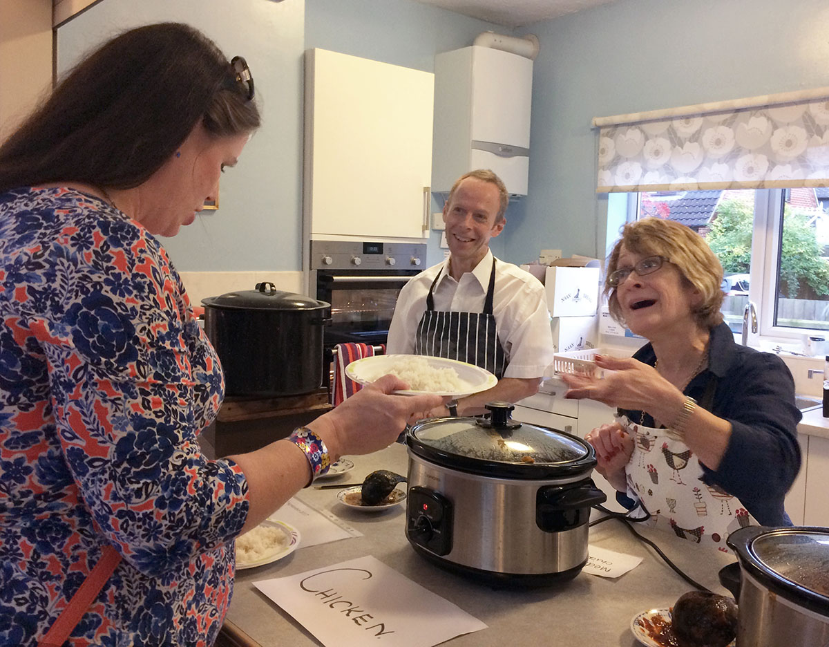 Villagers offer a choice of curries through the kitchen serving hatch as part of a fundraiser.