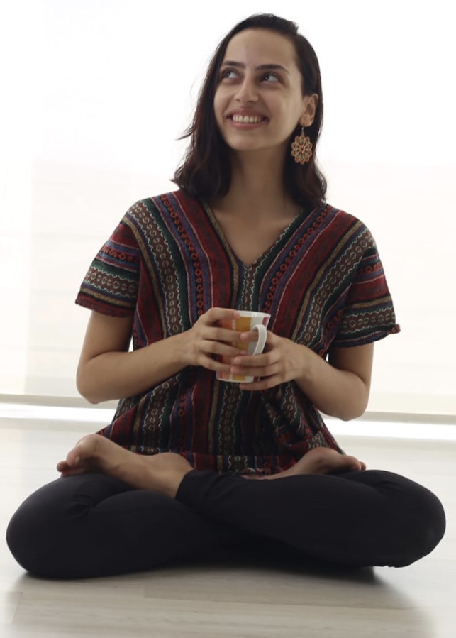 A woman sits with crossed legs, feet resting upward on each thigh.